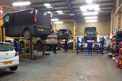 Vans and cars on lifts inside the J Millin & Son workshop